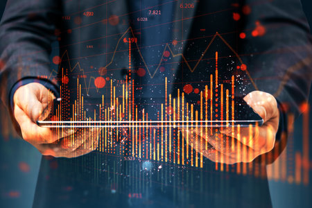 Close up of businessman hand using tablet with falling red candlestick forex chart on blurry...