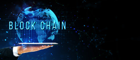 A hand holds a glowing tablet with a holographic globe and Blockchain text above it on a dark background. Concept of global digital technologyの写真素材