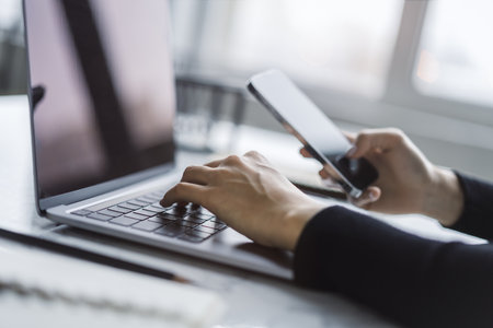 Set against a fuzzy office backdrop, the image presents a woman's hands typing on a modern laptop...