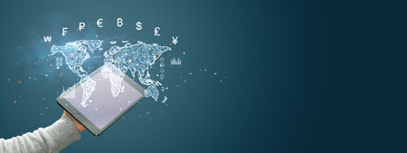 A holographic world map with currency symbols over a tablet held by a hand, on a dark background....