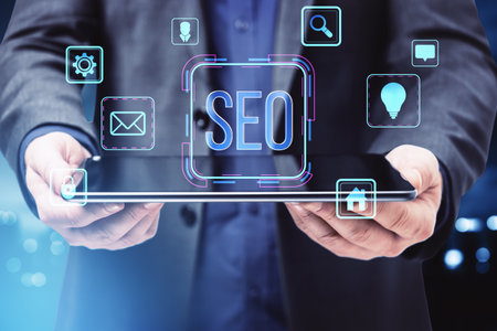 SEO concept with digital icons, a person holding a tablet, modern graphic style, on a blue background. Concept of internet marketingの写真素材