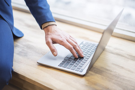 Set against a blurred office scene, the image reveals a close-up of a man's hands typing on a modern...
