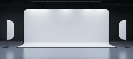 Minimalist display booth with blank white backdrop and two curved panels, set in a dark hall....