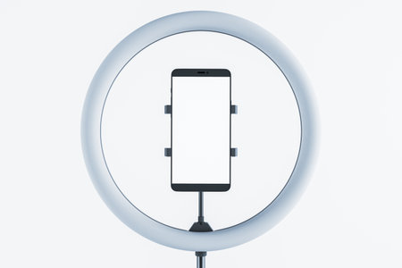 Smartphone held in a ring light mount, isolated on a clean white background, ideal for podcasting, blogging, or professional video production. 3D Rendering.の写真素材