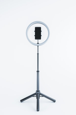 Ring light and smartphone attached to a tripod, isolated on a white background. 3D rendering of a...