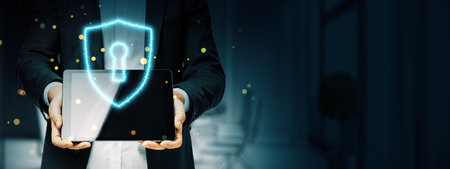 Businessman holding a tablet with a glowing shield and keyhole symbol, on a dark blurred background....