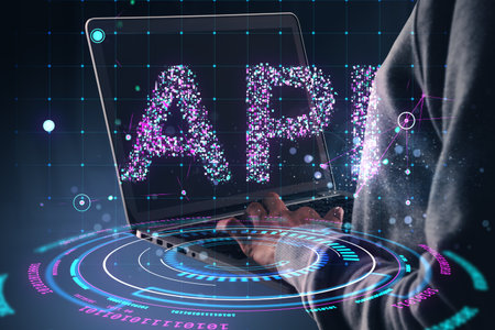 Person using laptop with glowing API text and futuristic holographic interface on dark background....