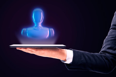 Hand holding tablet with holographic robot on dark background. Neon style. Concept of futuristic technologyの写真素材