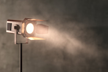 Retro spotlight emitting a bright beam through smoky air against a textured concrete backdrop. Concept of theater, cinema, and stage lighting. 3D Rendering.の写真素材