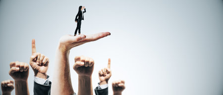 Businessperson standing on hand, support from team, on light background, concept of leadership and teamworkの写真素材