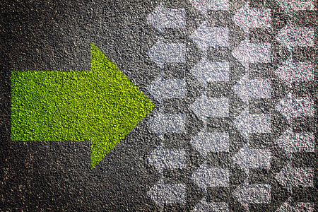 Green right arrow on asphalt with multiple fading white arrows. Abstract textured background. Concept of direction, guidance, and decision-makingの写真素材