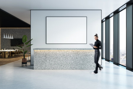 Contemporary office reception with an empty poster frame, terrazzo counter, and female worker in motion, set in clean urban interior spaceの写真素材