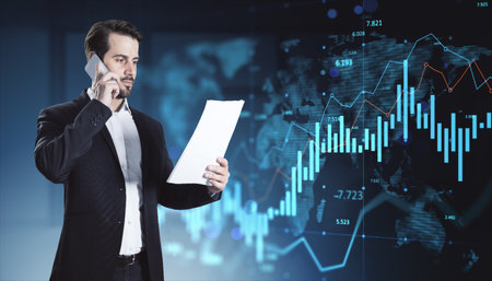 Businessman on phone holding documents, digital stock market chart overlay, dark blue background,...