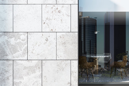 Textured stone tile wall beside reflective glass showing skyscrapers and chairs around table, clean...