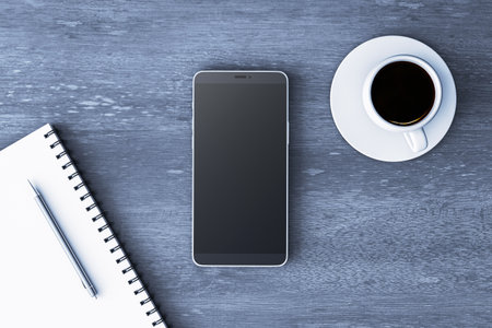 Top view of smartphone with blank screen, coffee cup, and notepad with pen on wooden background. 3D Rendering of office branding conceptの写真素材