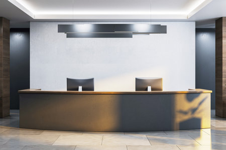 Sleek modern reception desk with dual monitors in a minimalist office interior, featuring soft lighting, wood accents, and tiled floor. 3D Renderingの写真素材