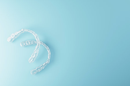 Transparent dental aligners shown in a creative 3D Rendering style, placed on a clean blue gradient background with copy space for medical conceptの写真素材