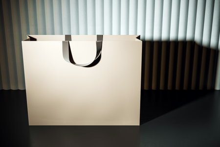 Blank shopping bag mockup with black handles standing on dark floor, curtain background, concept of modern luxury branding and retail promotion, 3D Renderingの写真素材