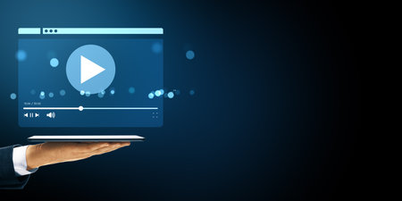 Hand holding tablet with floating digital video player interface, glowing light elements on dark background, concept of online streaming serviceの写真素材