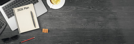 Workspace with notepad labeled 2026 Plan, laptop, coffee cup, and office supplies on dark wooden desk background. Business planning concept. 3D Renderingの写真素材
