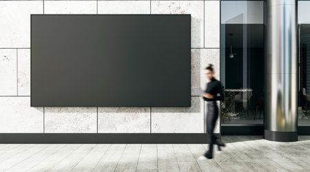 Empty black billboard on wall of contemporary building with businesswoman walking by, promoting advertising and urban business concept outdoorsの写真素材