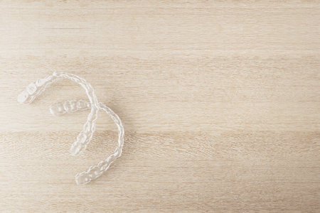 Transparent dental aligners on light wood background, realistic style, represents orthodontic care and dental hygiene concept. 3D Renderingの写真素材