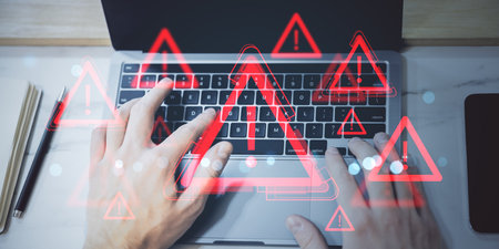 Hands typing on laptop with red warning icons overlay, hologram style on light background, concept...