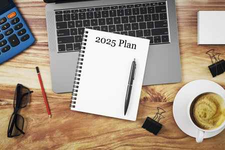 Notebook labeled 2025 Plan on wooden desk with pen, laptop, coffee cup, and calculator from top view. 3D Renderingの写真素材