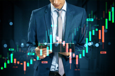 Businessman using tablet with candlestick chart overlay, digital style, dark office background. Concept of online trading and fintech analysisの写真素材