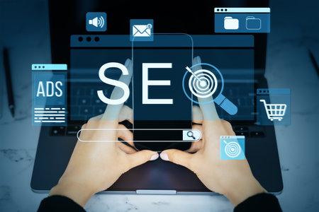 Hands holding smartphone in front of laptop with digital SEO icons overlay, representing online marketing, ecommerce, and search optimization toolsの写真素材