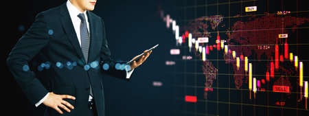 Businessman using smartphone in front of digital stock market chart showing red downward trend on dark background, concept of global crisisの写真素材