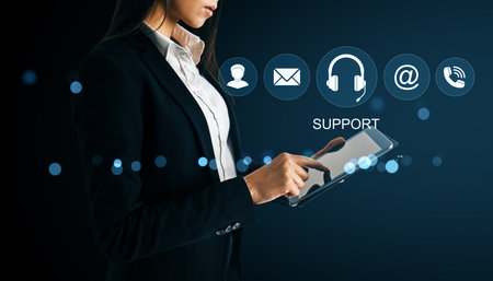 Female professional holding tablet with online support icons, realistic style, on dark background. Concept of digital help and communicationの写真素材