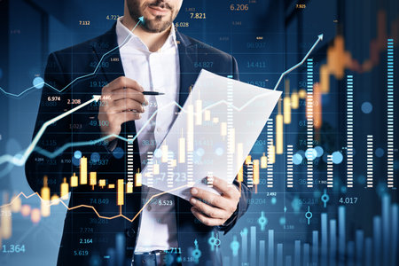 Businessman holding paper and pen with financial graphs overlay, modern digital style, dark blurred background, concept of market analysisの写真素材