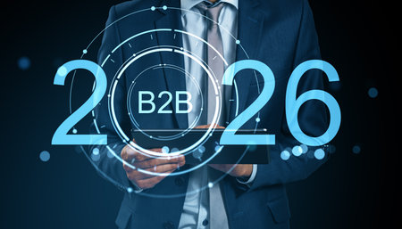 Businessman in suit holding tablet with 2026 B2B digital hologram interface, glowing blue on dark background, symbolizing future business trendsの写真素材