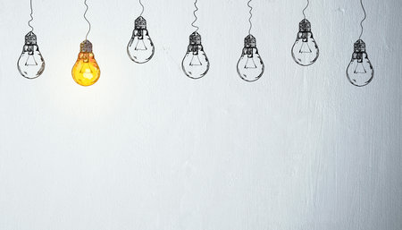 Hand-drawn lightbulbs hanging on white wall background with one glowing yellow bulb, representing leadership, creativity, and innovation. 3D Renderingの写真素材