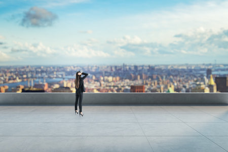 Female businesswoman on a rooftop with city skyline in background under blue sky, representing future thinking and vision in urban settingの写真素材