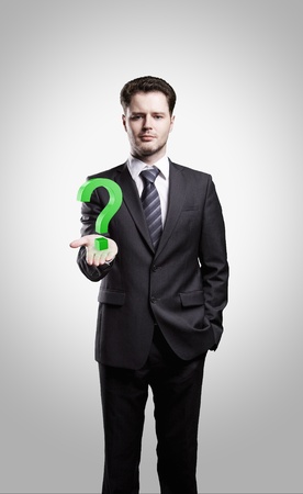 Young  businessman with a question mark on his hand. On a gray backgroundの写真素材