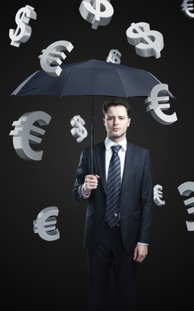 Business man with umbrella under evro and dollar signs rainの写真素材
