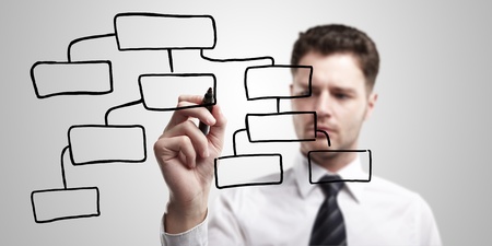 Businessman designing a plan on a glass screen with black marker. 