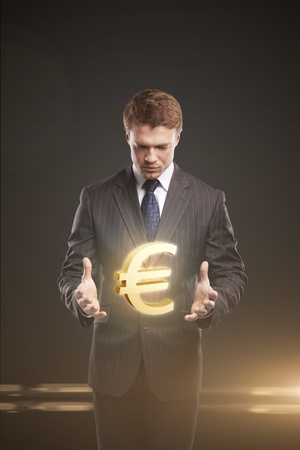 Young  businessman chooses a Gold Euro Sign. On a black backgroundの写真素材
