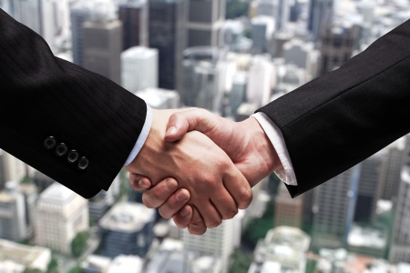 businessmen shaking hands on background of cityの写真素材