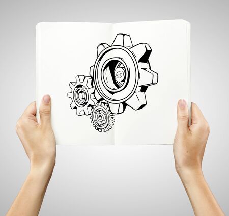 drawing gears in book on a white backgroundの写真素材