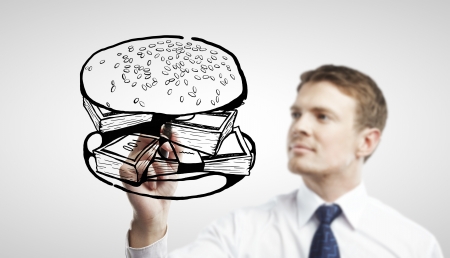businessman drawing sandwich out of moneyの写真素材