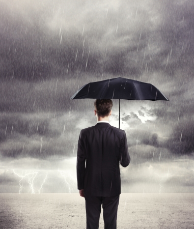 Businessman with umbrella in rainの写真素材