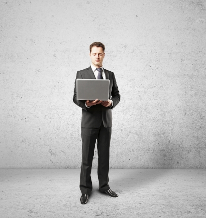 businessman with laptop on concrete roomの写真素材