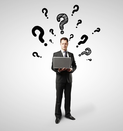 businessman with laptop and question marksの写真素材