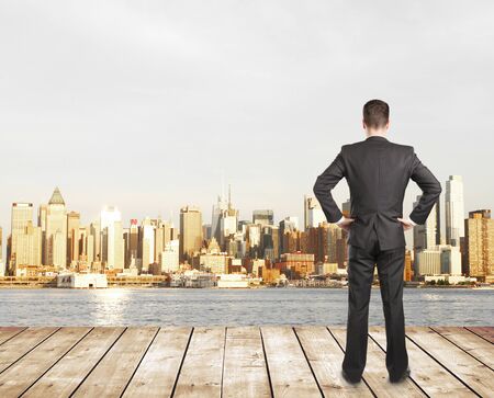 Businessman standing on pier and modern cityの写真素材