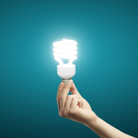 energy saving lamp in hand on blue backgroundの写真素材