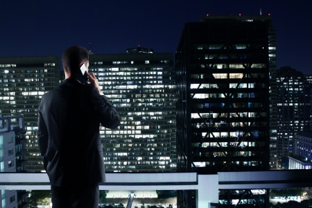 man with phone looking to night cityの写真素材