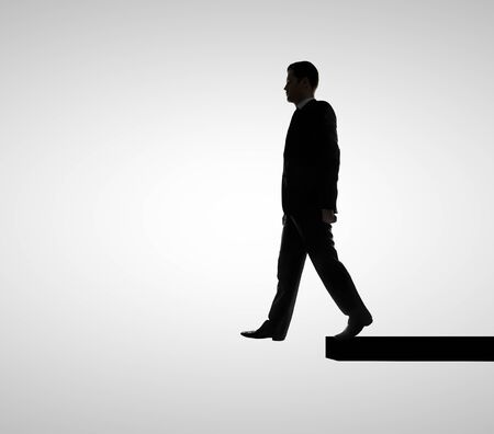 businessman walking on edge  on white backgroundの写真素材